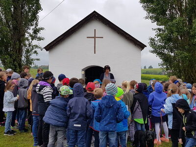 Lehrkräfte und Kinder der Klassen 1 und 2 beten und singen gemeinsam an der Kapelle.
