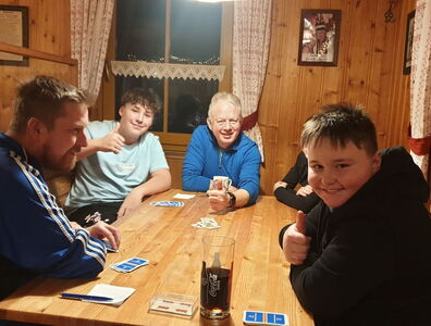 Schüler und Lehrer beim Karten spielen in einer Hütte